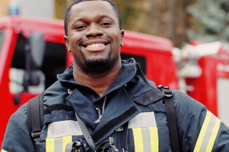 Firefighter smiling in front of a firetruck